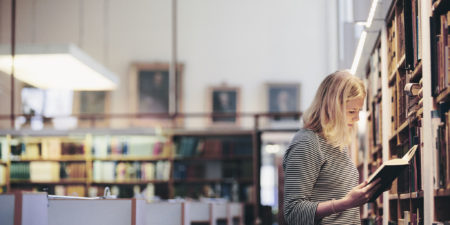Studerande som läser bok i biblioteket