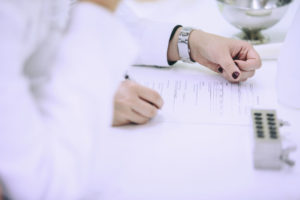 Hand som fyller i blankett.