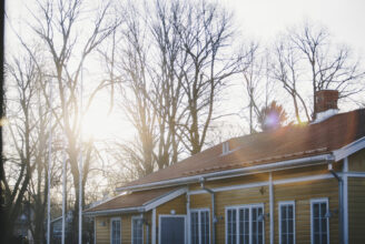 Gult hus i Åbo med solljus mellan trädtopparna.