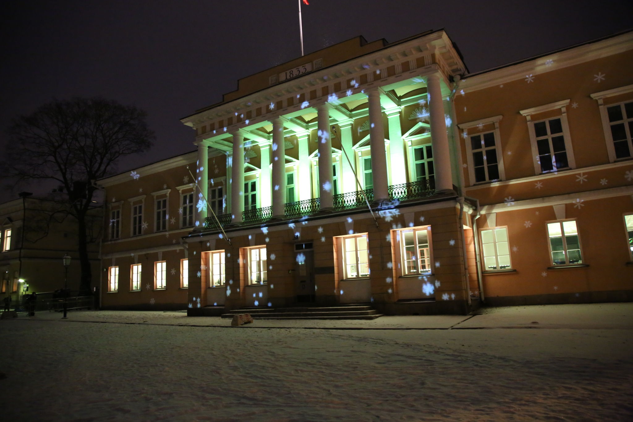 Åbo Akademis huvudbyggnad upplyst i grön färg. Fotot taget under i mörker.