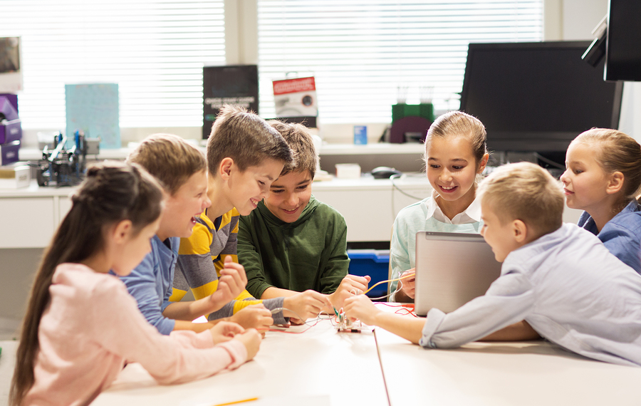 education, children, technology, science and people concept - group of happy kids with laptop computer building robots at robotics school lesson