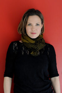 Psykolog Julia Korkman framför röd vägg.