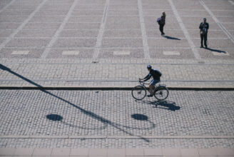 Cyklist cyklar på kullerstensgata.