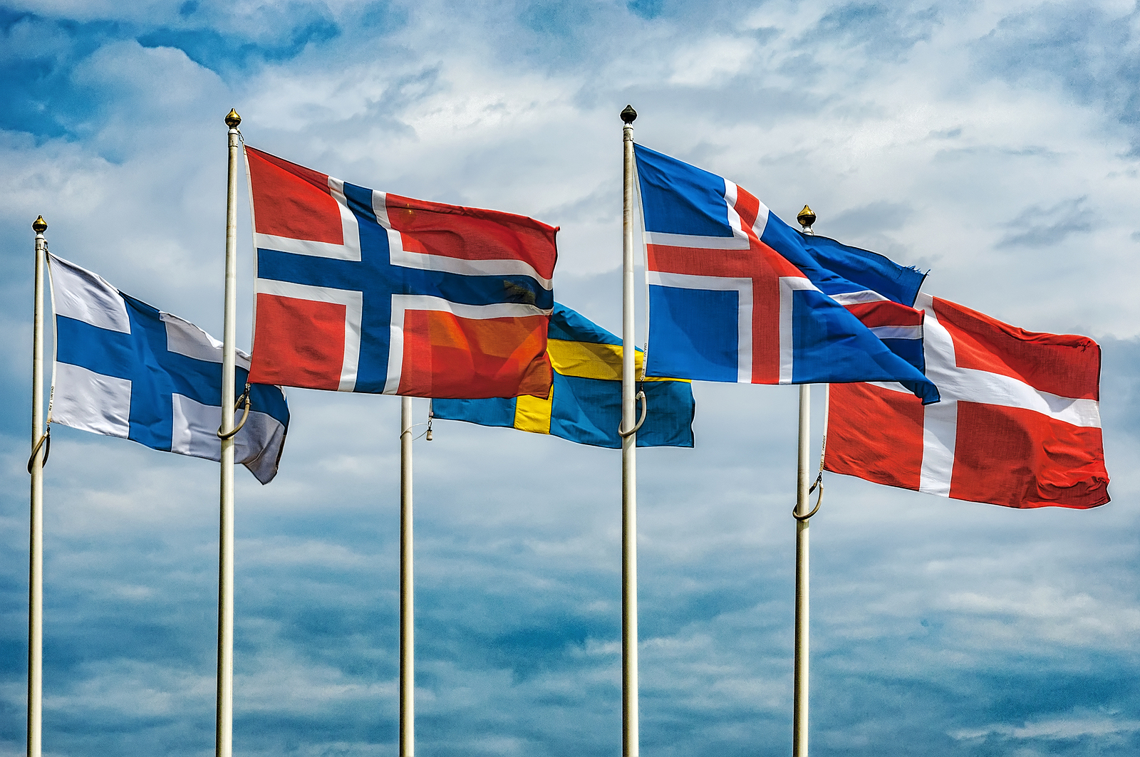 The flags of the countries of Scandinavia waving in the sky of a beautiful summer day.