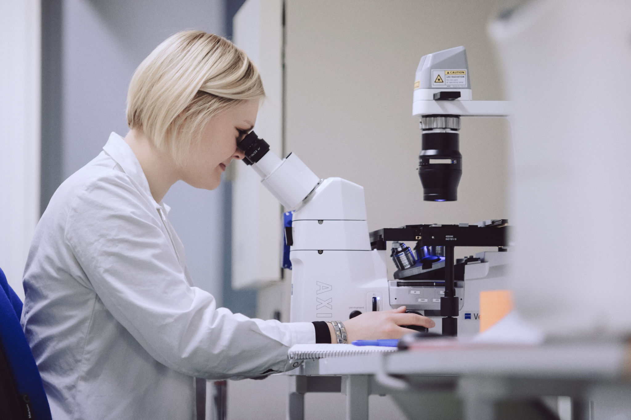 Kvinna ser i mikroskop.