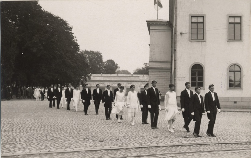 Åbo Akademis första promotion 1927. Promovender gående i procession över domkyrkotorget. I bakgrunden gamla akademihuset och landshövdingens magasin.