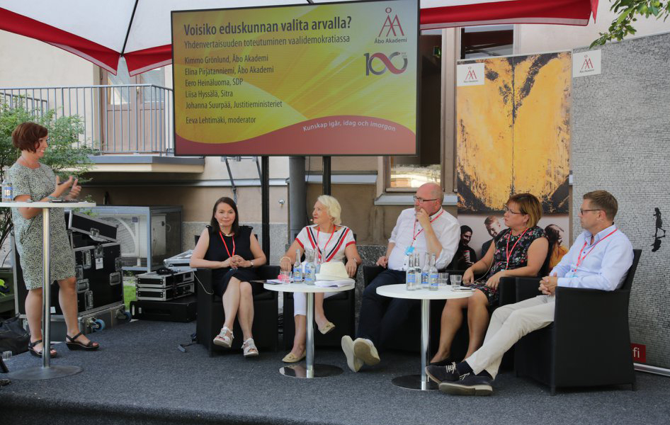 Personer sitter på rad i en paneldebatt