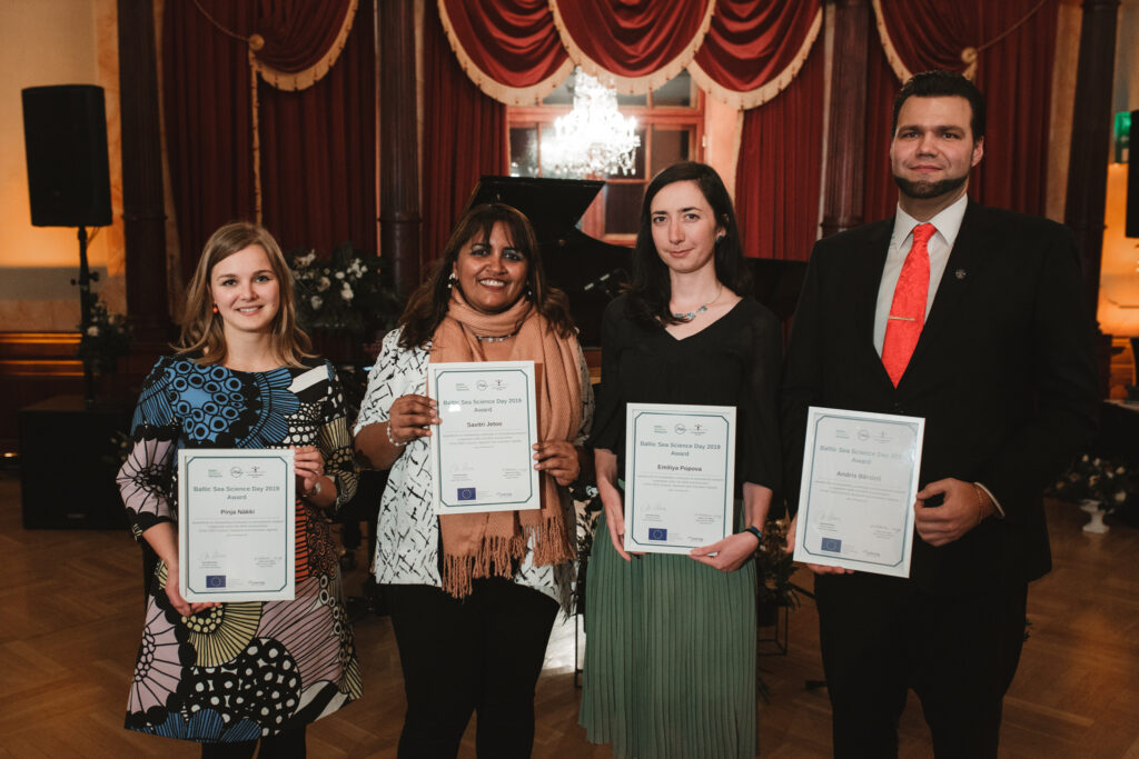 Four young award winners standing with diplomas in their hands. 