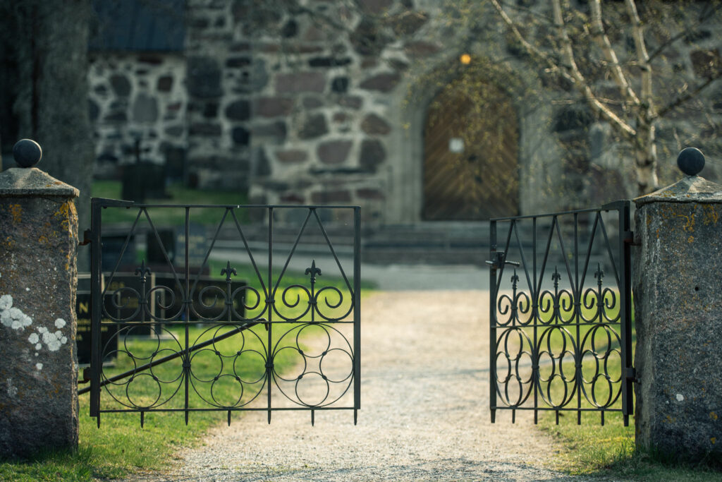 Halvöppen grind till kyrkogård.