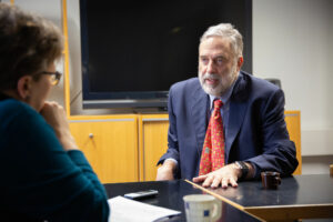 James Fishkin sittande vid ett bord, pratande med en journalist.