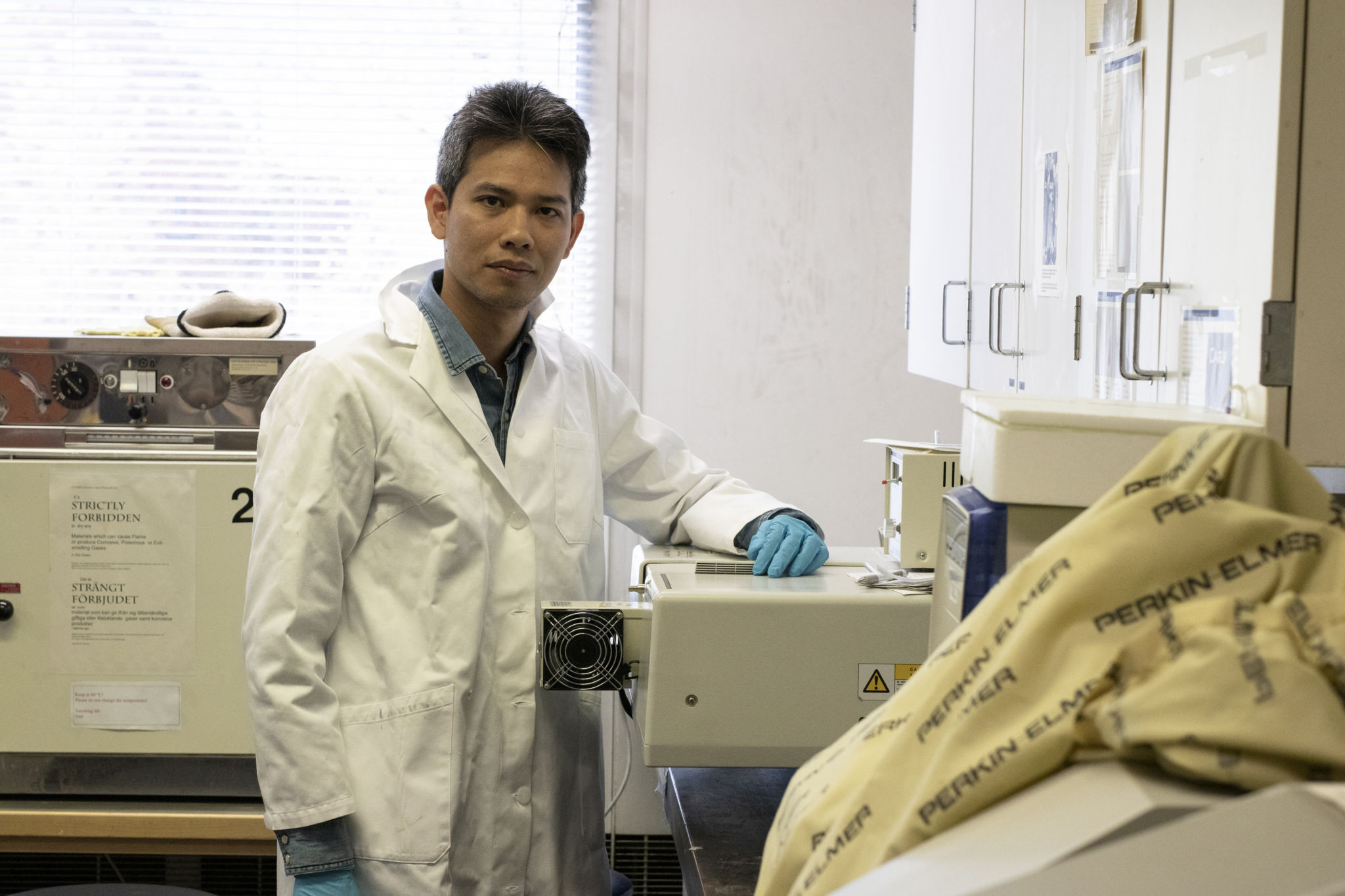 Tan Phat Huynh iförd laboratoriekläder i ett laboratorium.