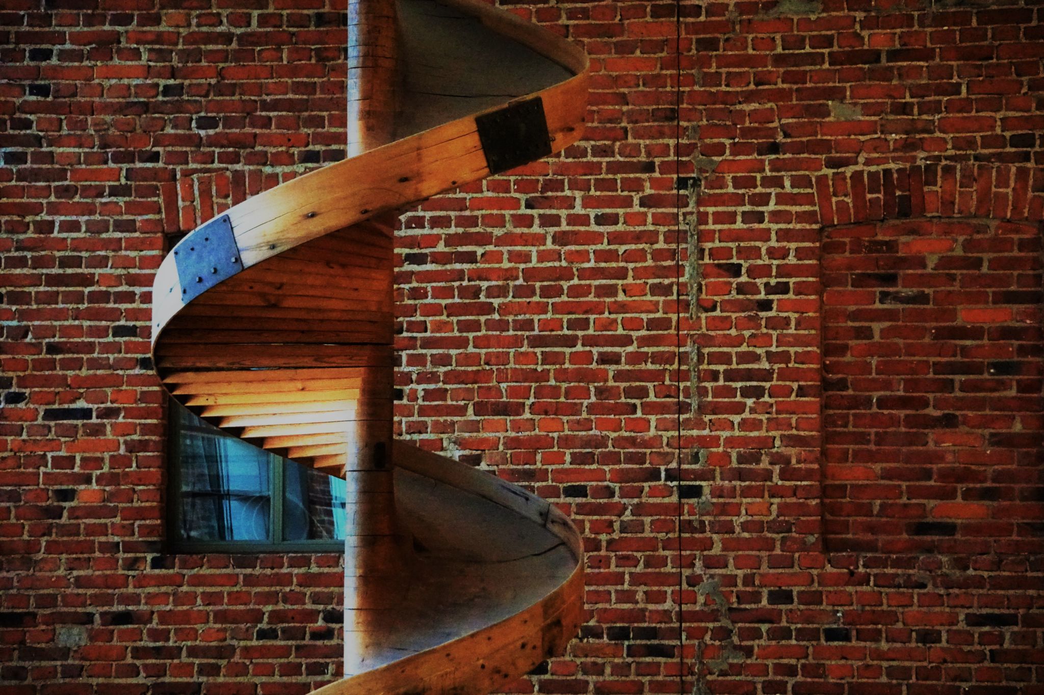Wooden spiral in front of a brick wall