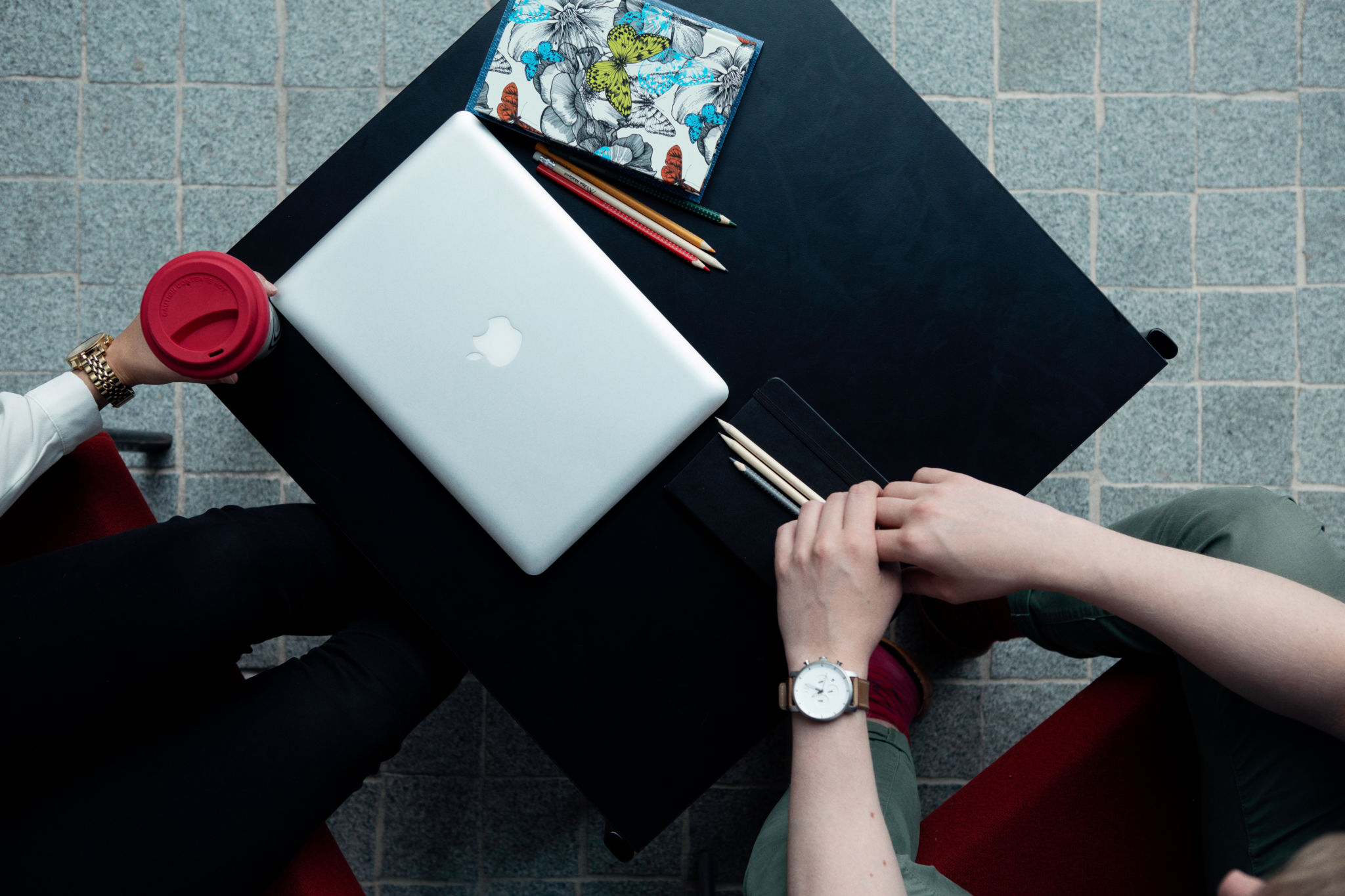 Dator, häfte och pennor på ett bord.