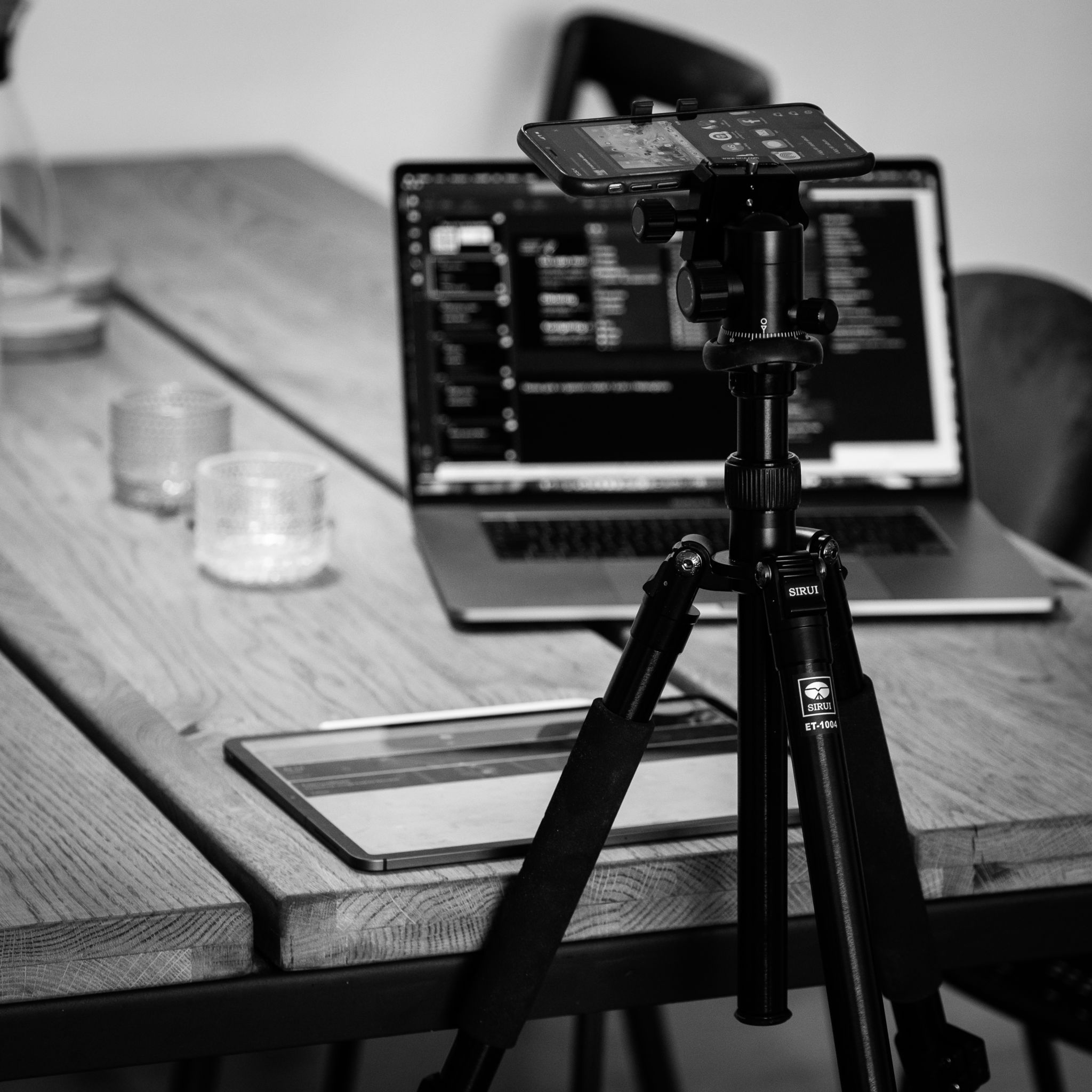 Bild på telefon som är riggad på ett stativ. I bakgrunden syns en laptop på ett bord.
