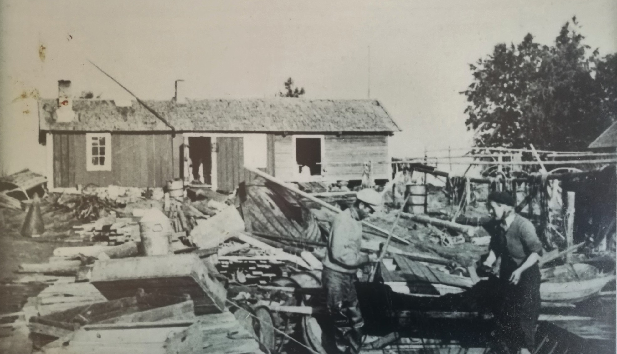 svartvit bild på en kvinna och en man som jobbar i stranden med fiskebragder