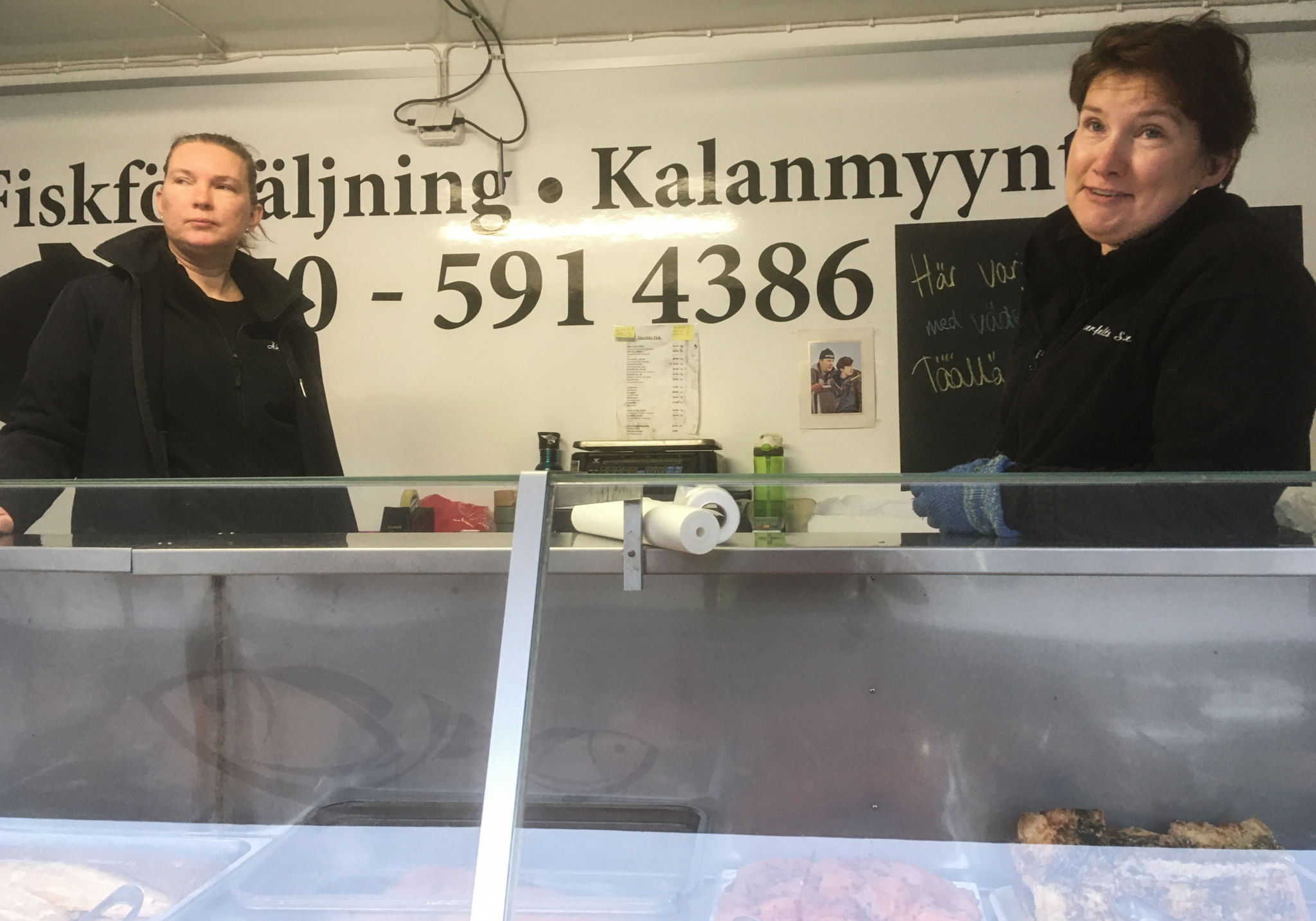 Två kvinnor bakom en fiskförsäljningsdisk.