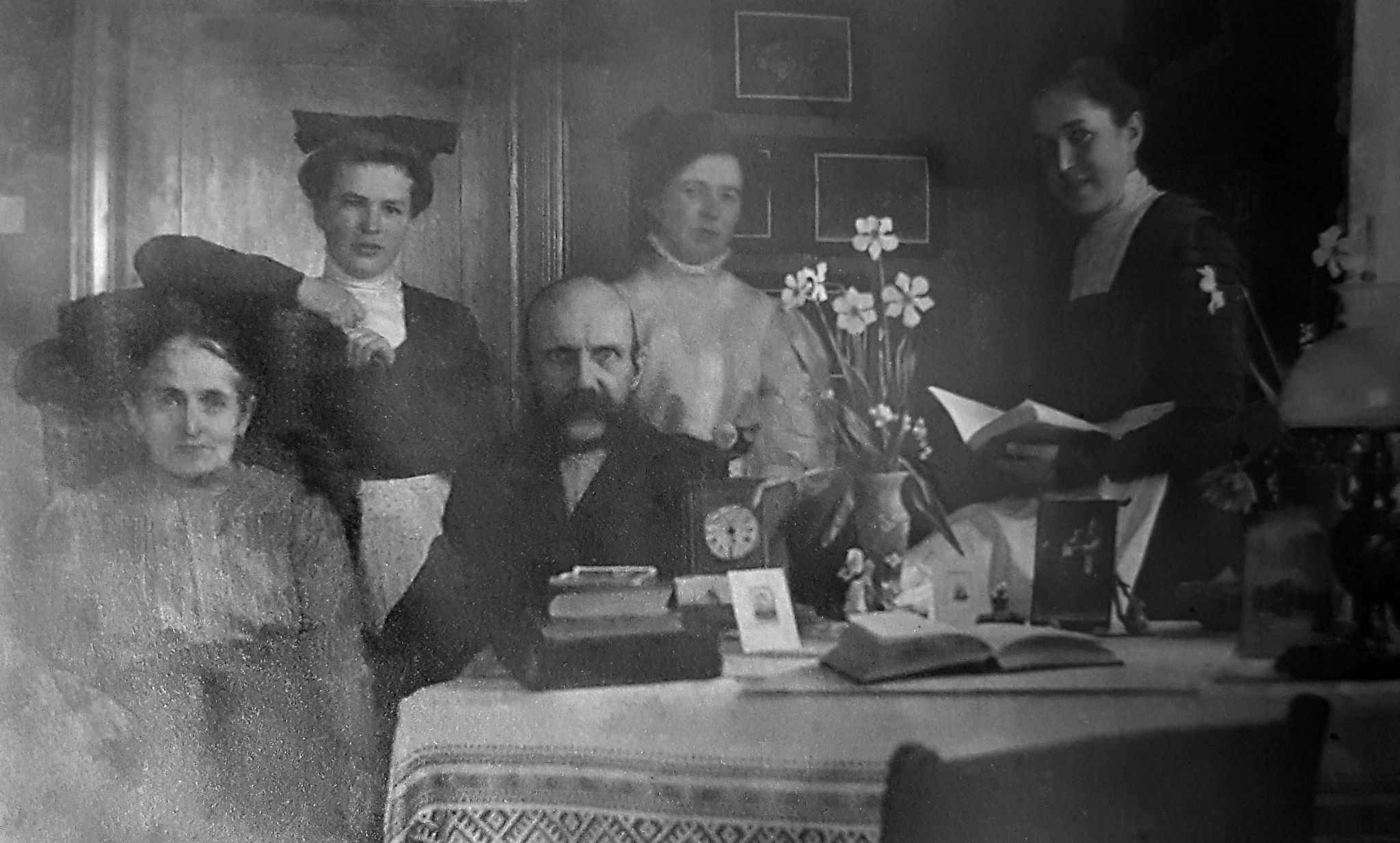 En familj på fem personer samlade för porträtt bakom ett bord. Svartvit bild.