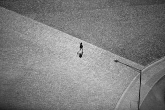 En ensam person mitt på en gata eller ett torg.