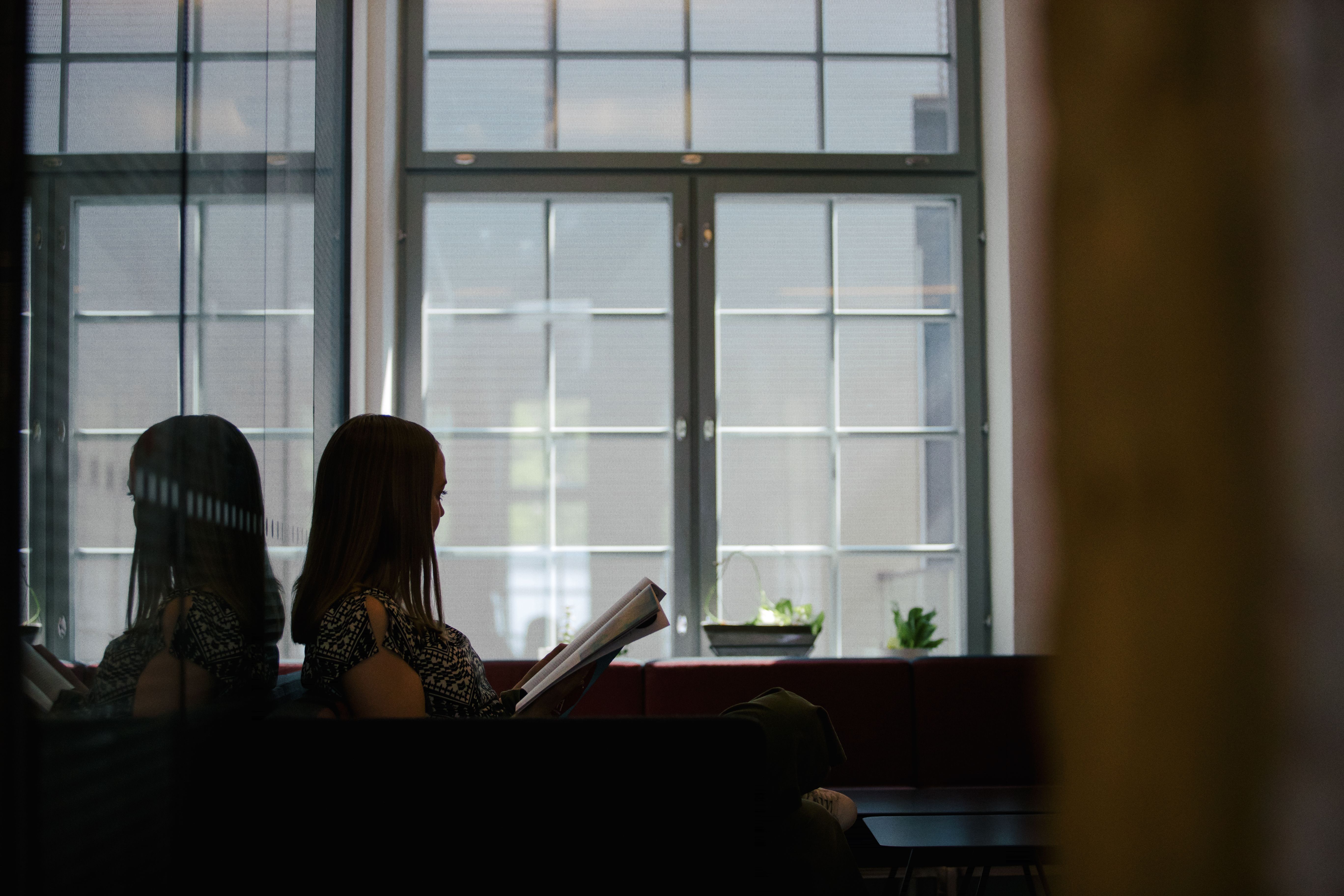 En studerande sitter läsande vid ett fönster.