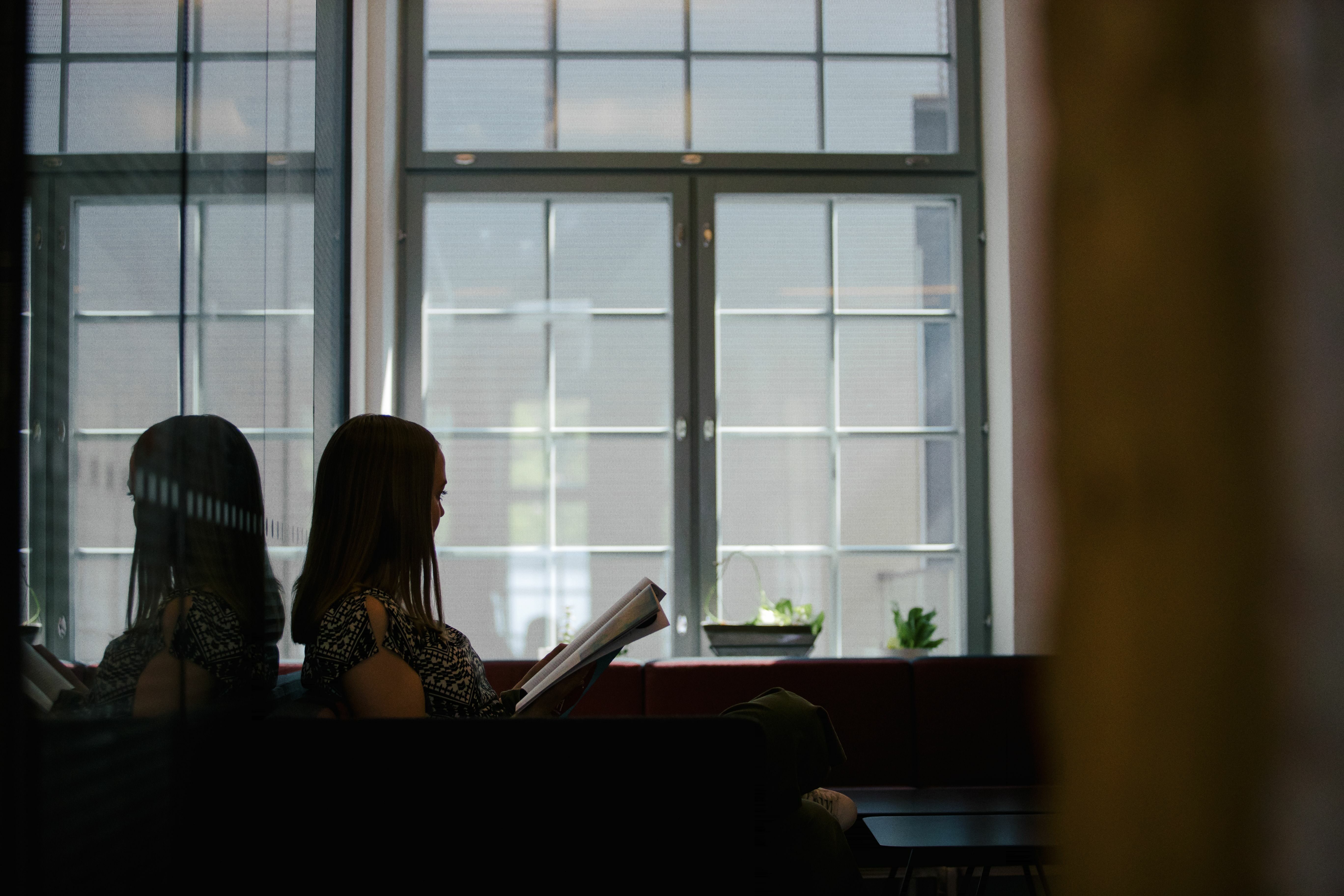 En studerande sitter läsande vid ett fönster.