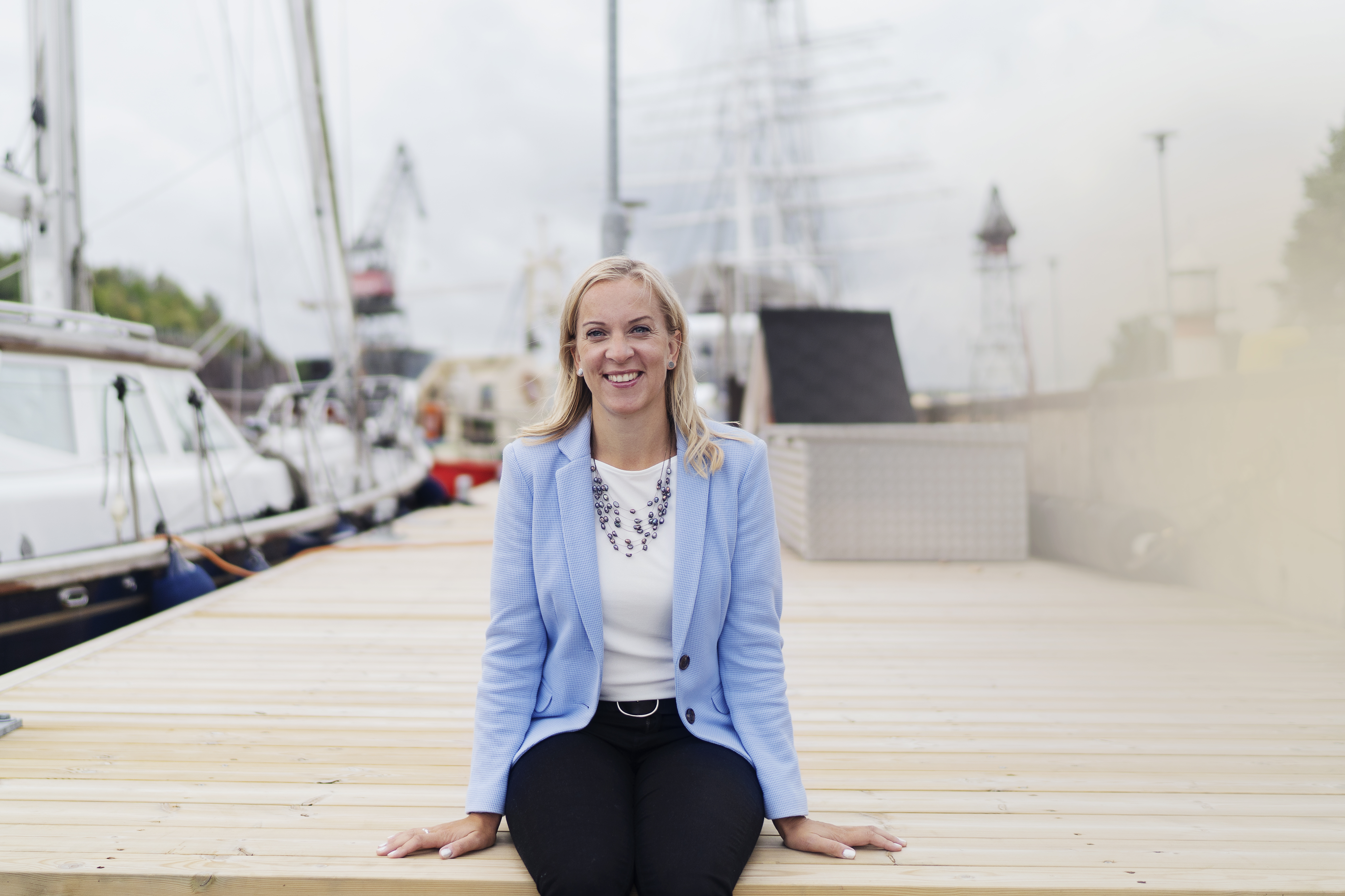 En leende Sandra Bergqvist sitter på en brygga.