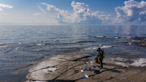 Forskare iklädd dykardräkt vid havsstrand.