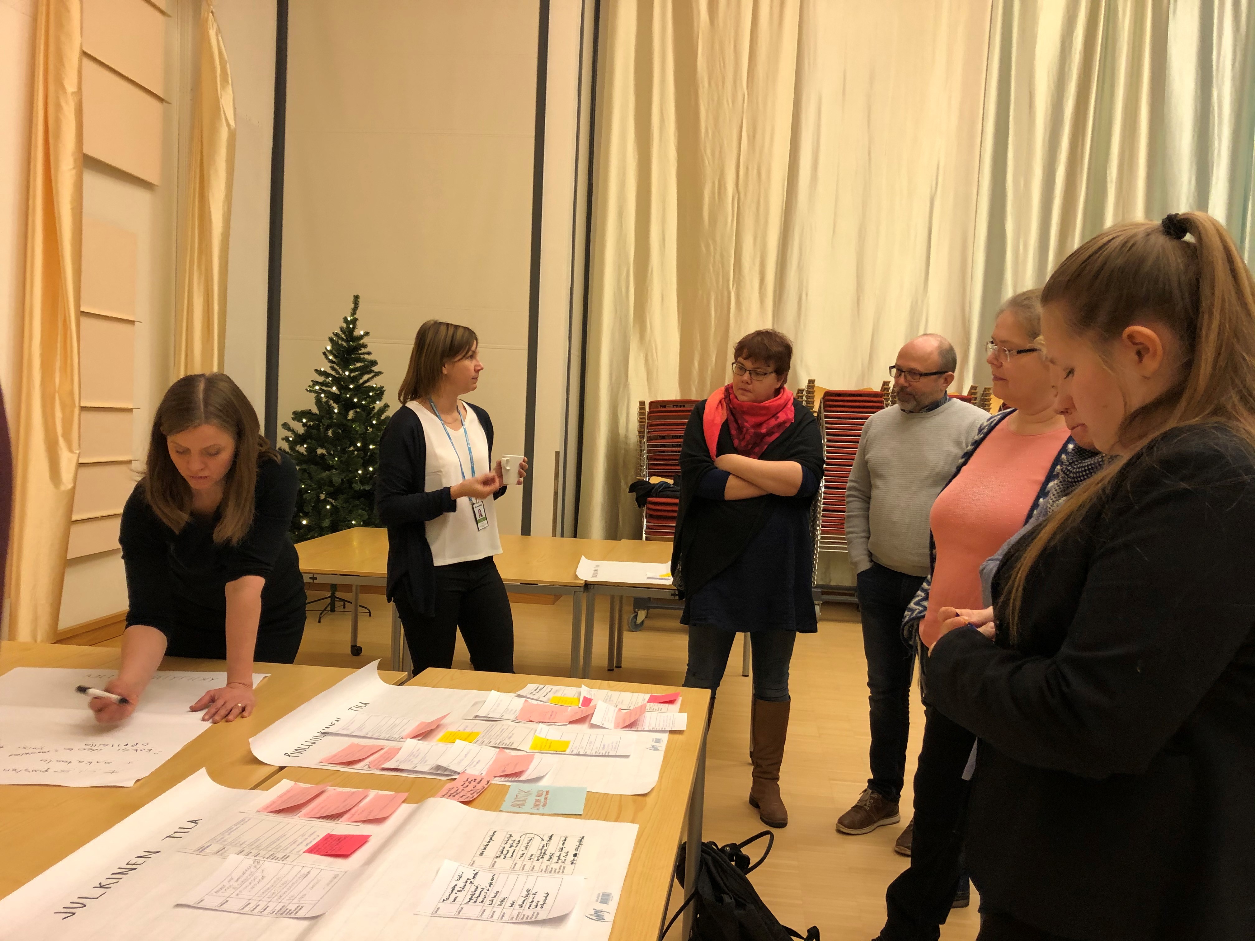 En grupp människor står vid ett bord och skriver på post-it-lappar.