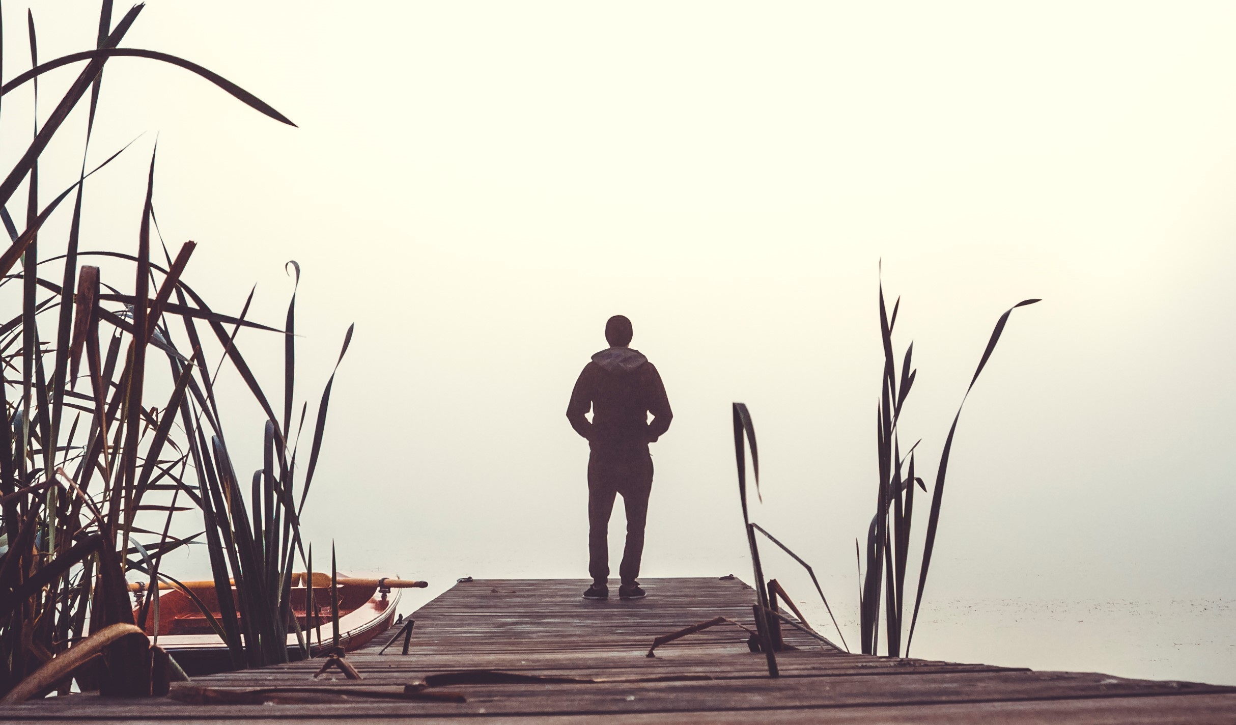 En man står med ryggen ot kameran på ändan av en brygga.