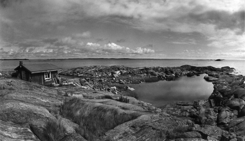 En svartvit bild över en stenig ö och havet.