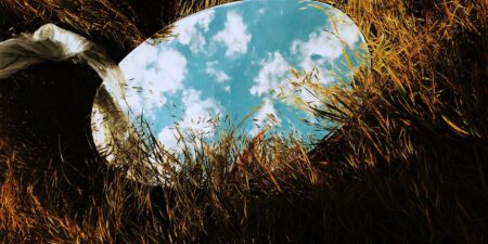 Spegel som ligger på gräset och reflekterar molnen på himlen.