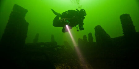 En undervattensbild på en dykare med syrgastuber på ryggen.