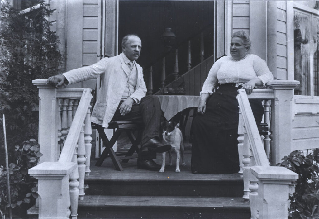 En gammal svart-vit bild med ett par som sitter på en veranda.