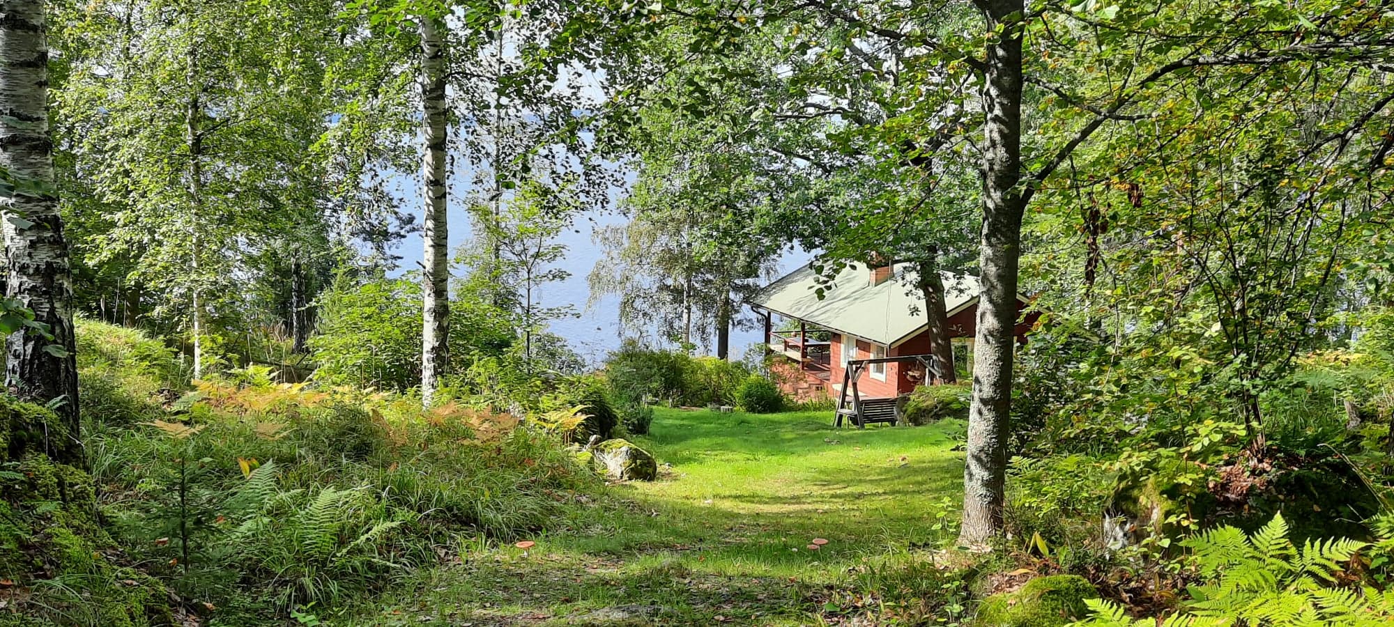 Sommarstuga fotograferad bakifrån mot stranden den vetter mot.