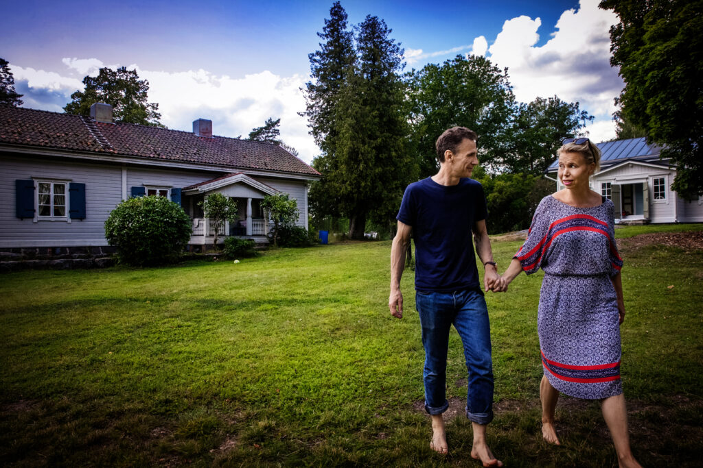 En man och en kvinna går hand i hand över en gräsmatta. I bakgrunden ett hus.