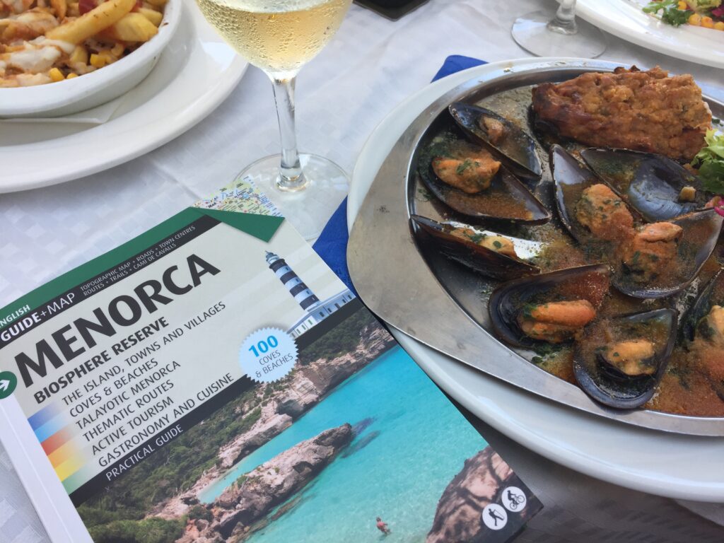 A table with a portion of mussels and a guide about Menorca biosphere reserve.
