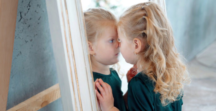 Flicka studerar sig själv i spegeln
