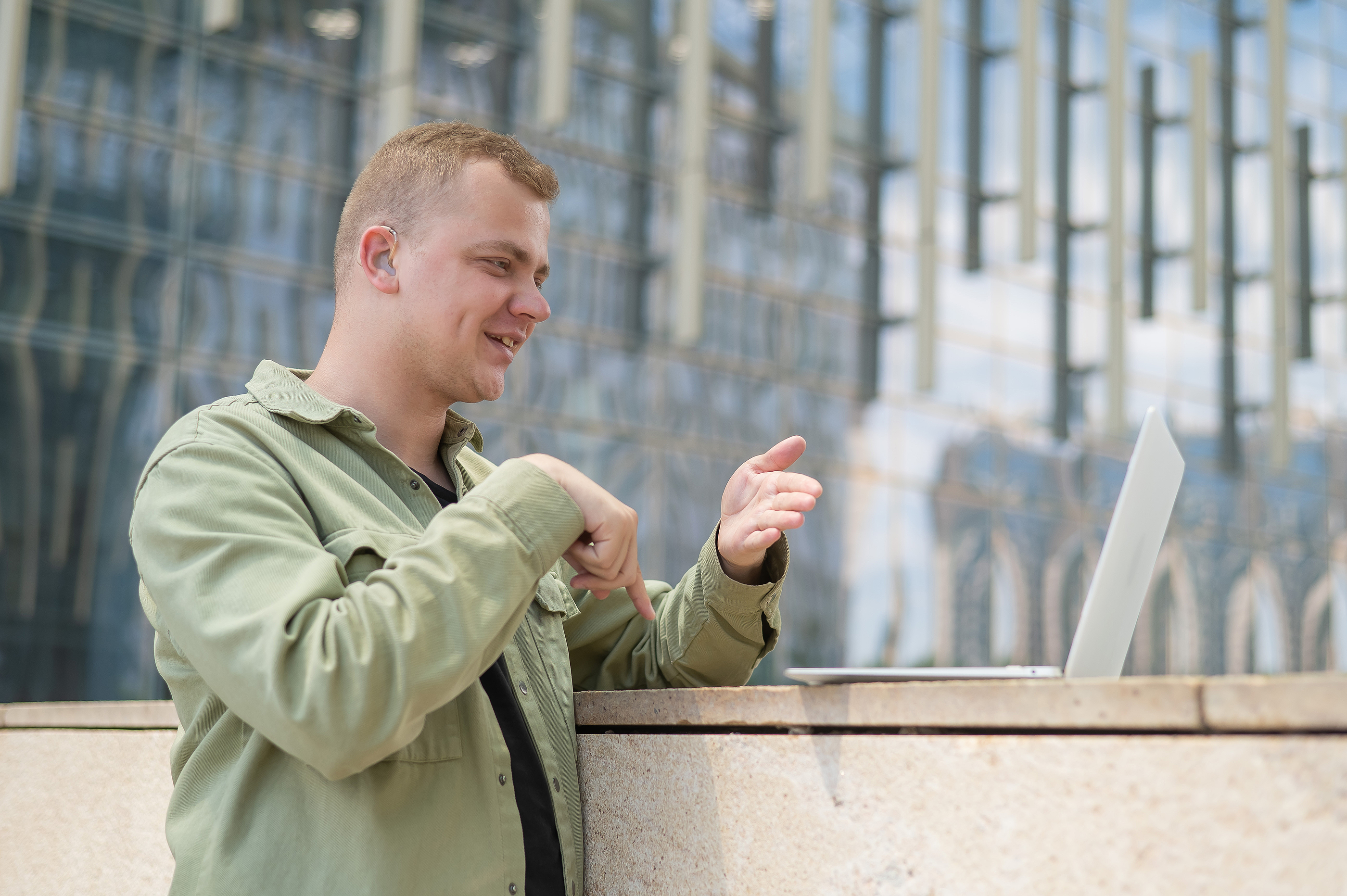 En ung man talar teckenspråk till en datorskäm.
