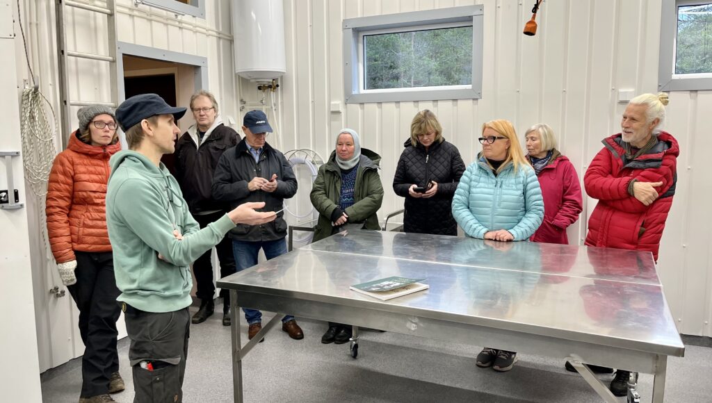 En grupp människor står runt ett blankt bord i rostfritt stål.