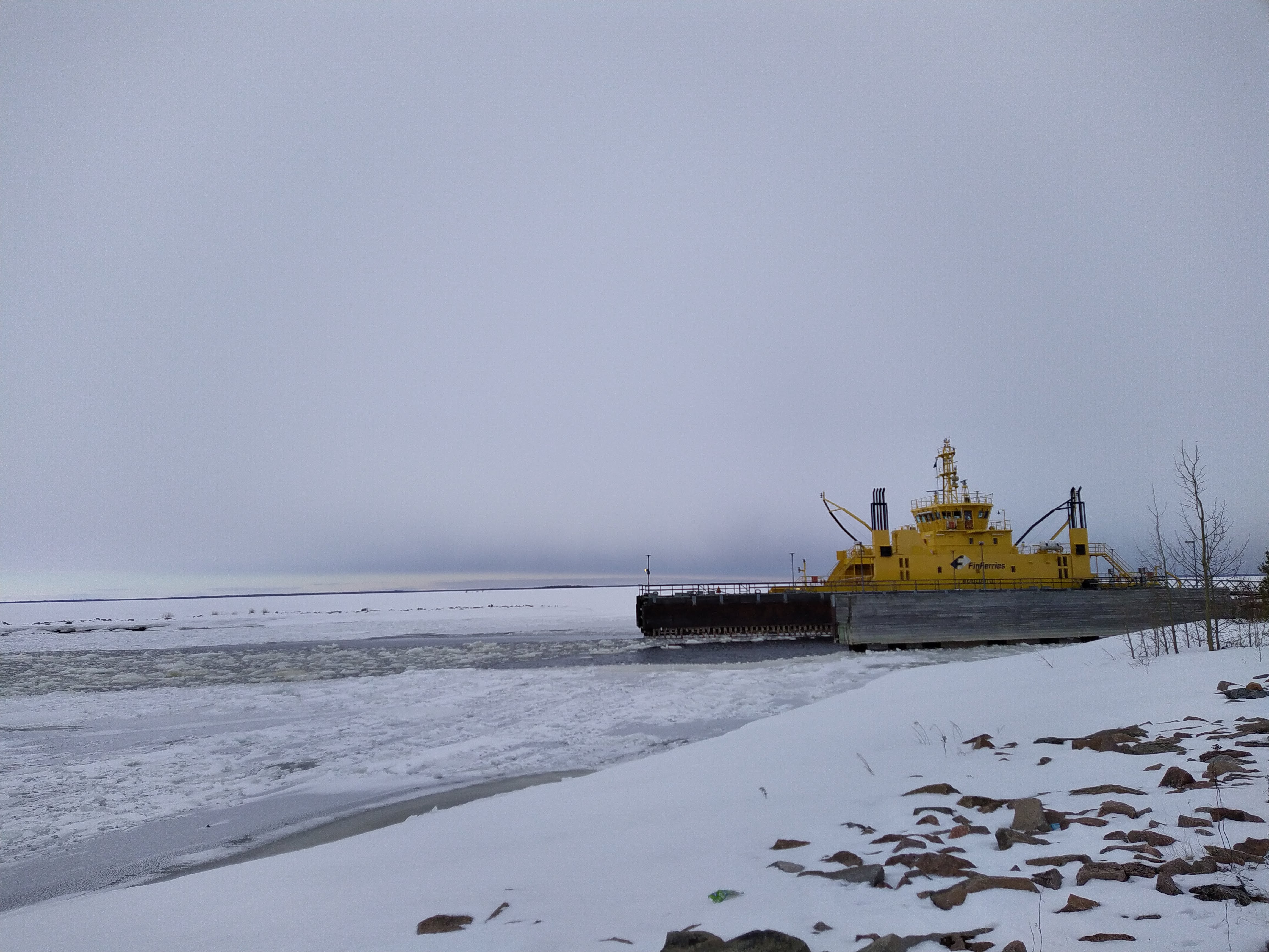 En gul landsvägsfärja vid en vinrtig strand.