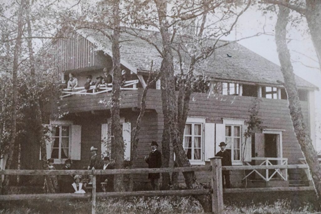 Svart-vit gammal bild på ett stort hus i två våningar.