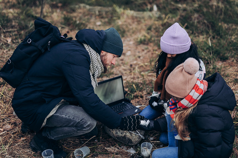 Lärare som går igenom en uppgift med två elever utomhus.