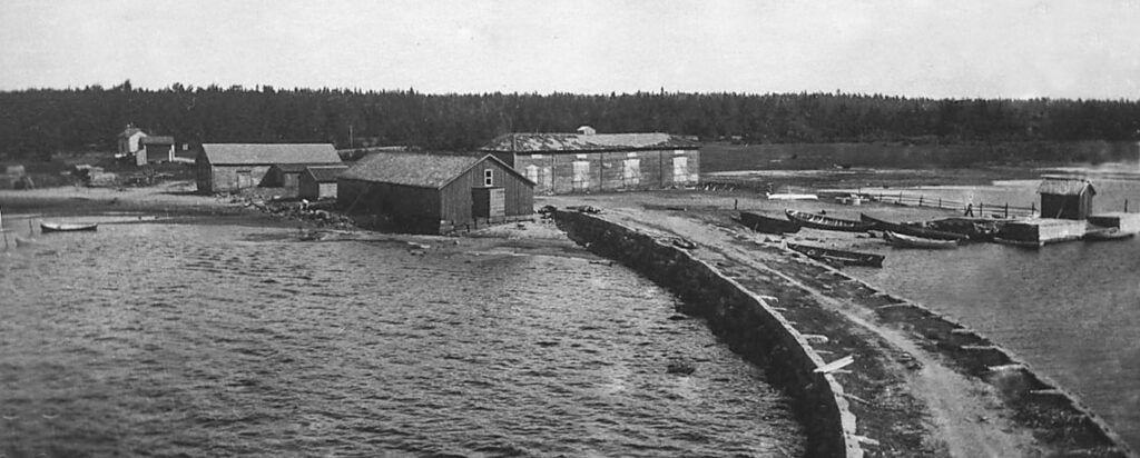 GAmmal svart-vit bild över ett båthus och en strand.