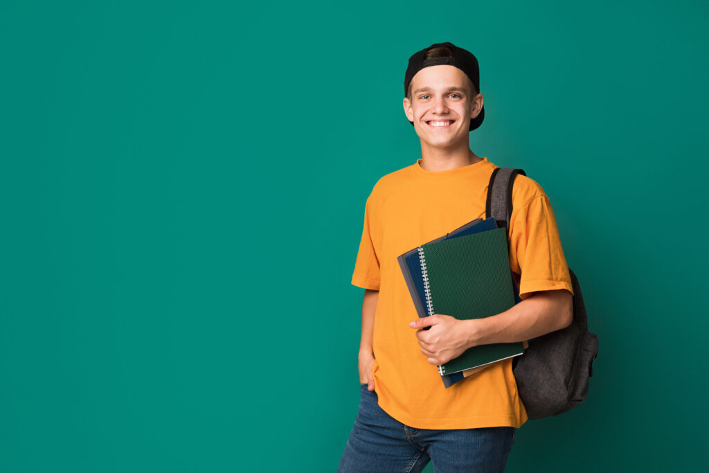 Glad kille med skolväska och böcker