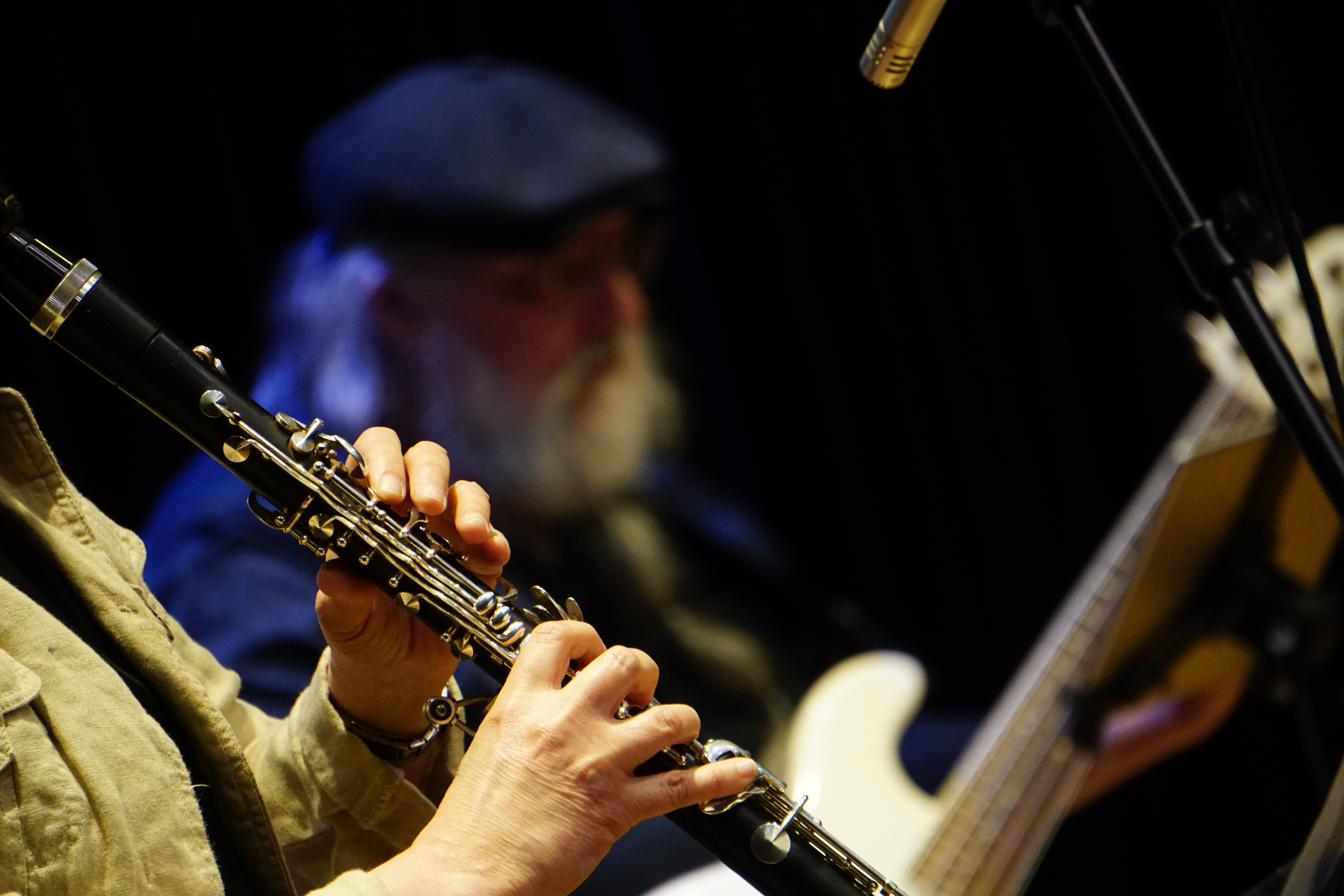 Närbild på klarinett. I bakgrunden Stefan Kilju med en elbas.