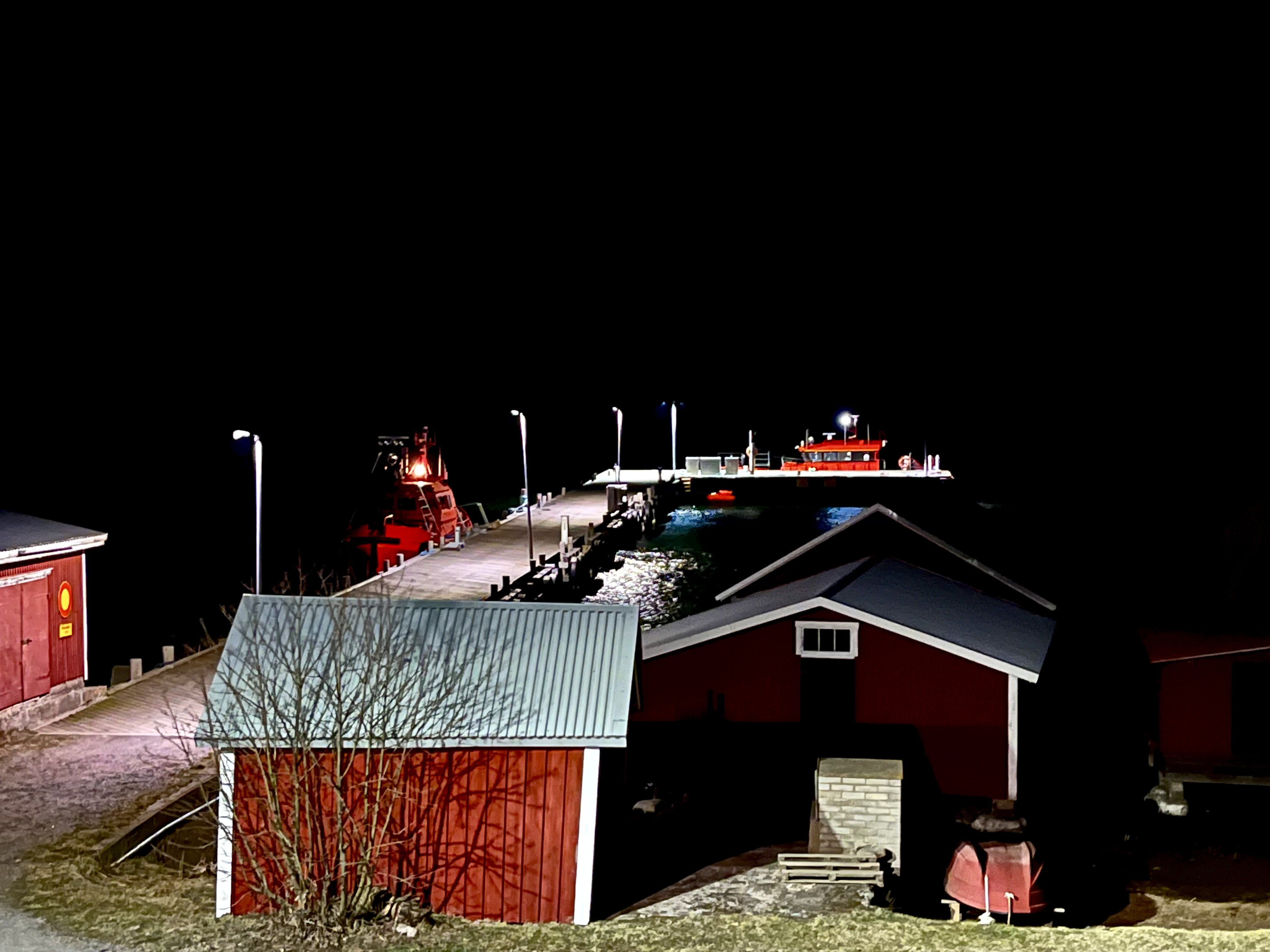 Två röda lotsbåtar förtöjda vid bryggan på Utö. det är mörkt.