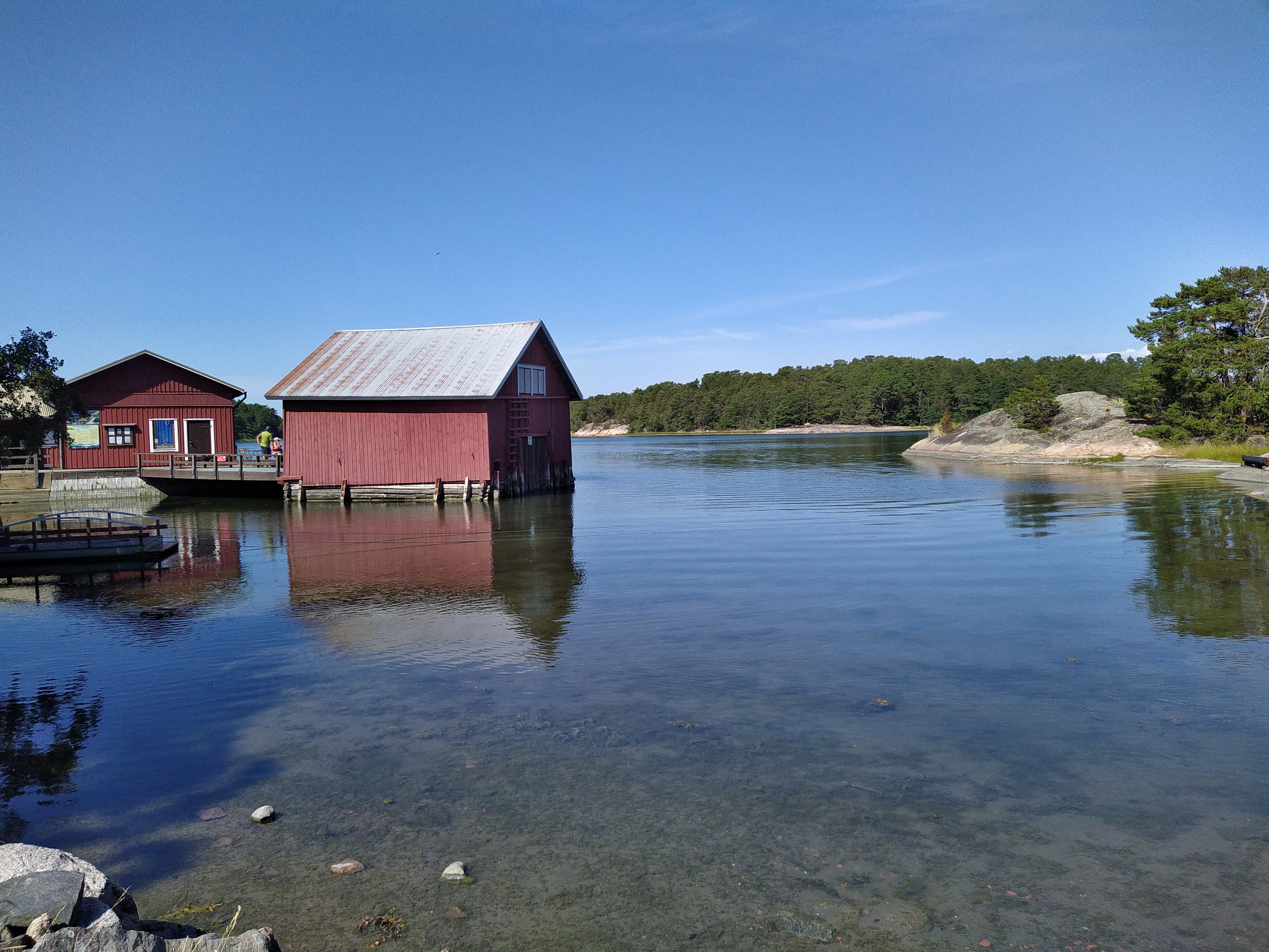 Ett rött båthus och väldigt klart havsvatten.