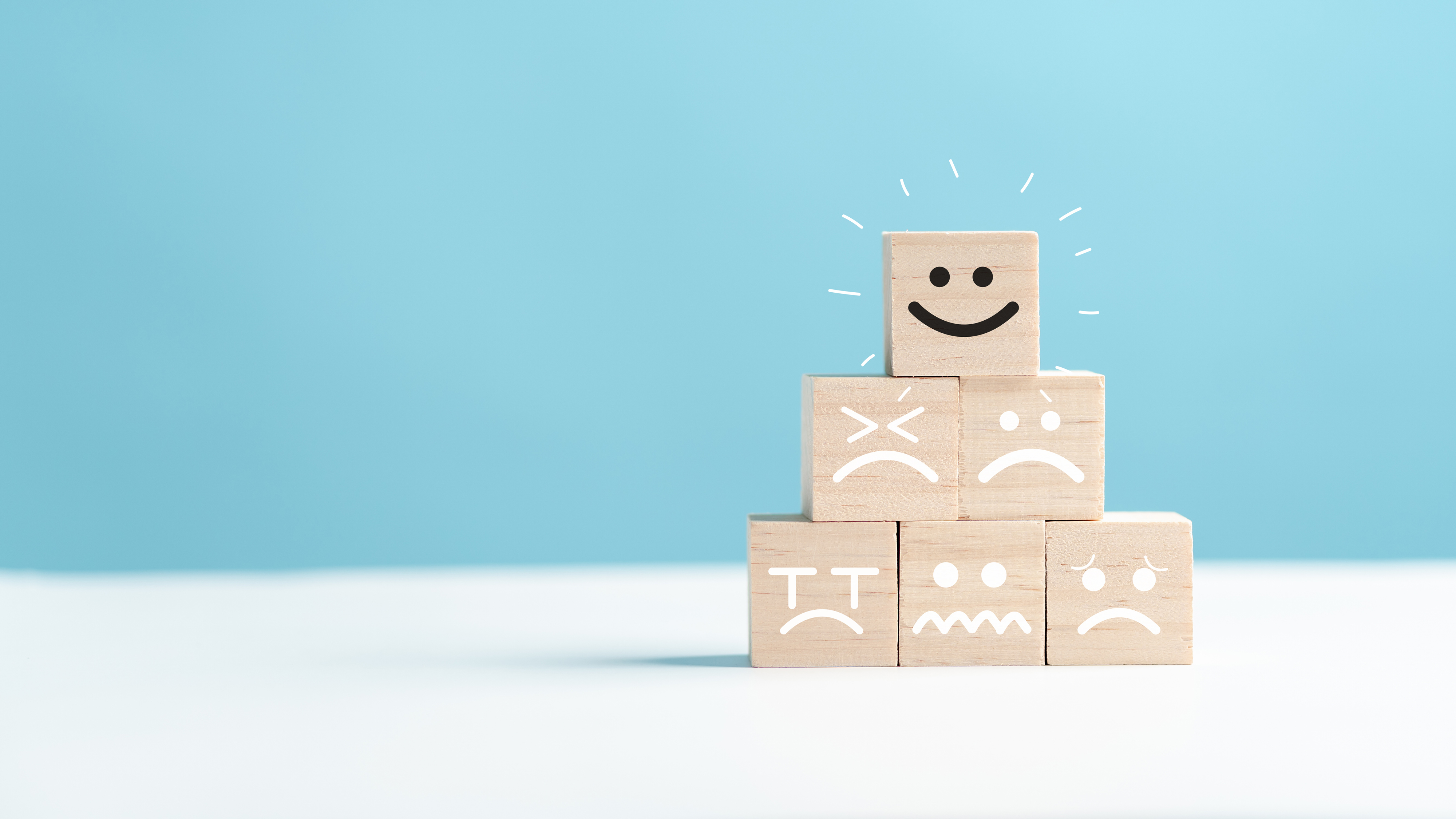 En glad träkub ovanpå en stapel med ledsna träkuber.