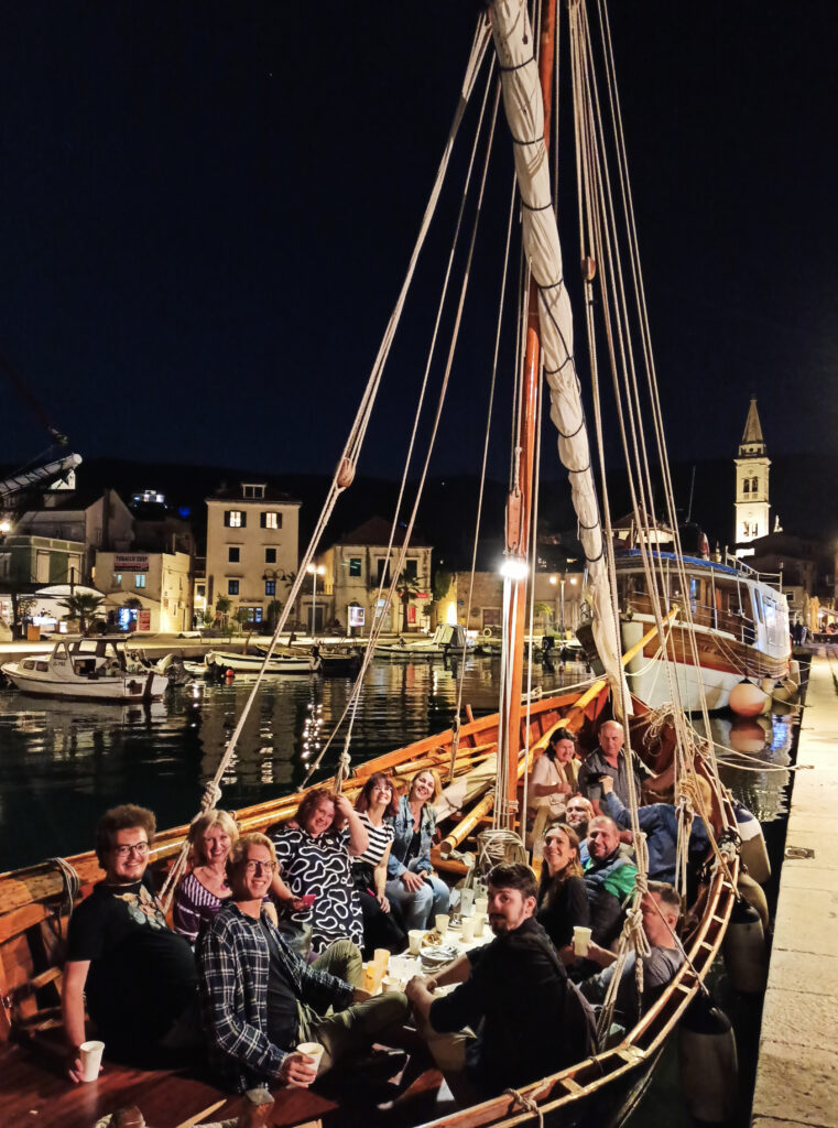 Stämningsfull kväll i en hamn, människor sitter i en segelbåt.