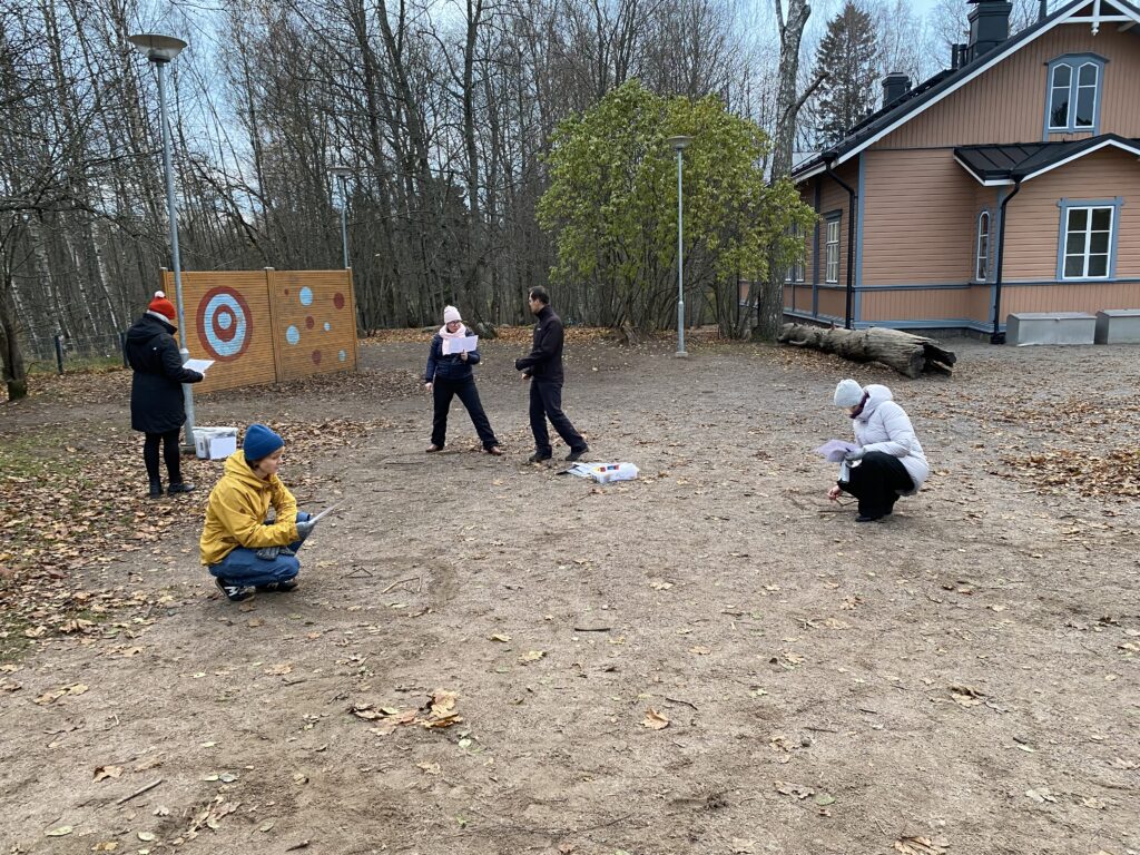 Några lärare på skolgården som alla koncentrerat gör sin egna uppgifter och tittar på olika saker. 