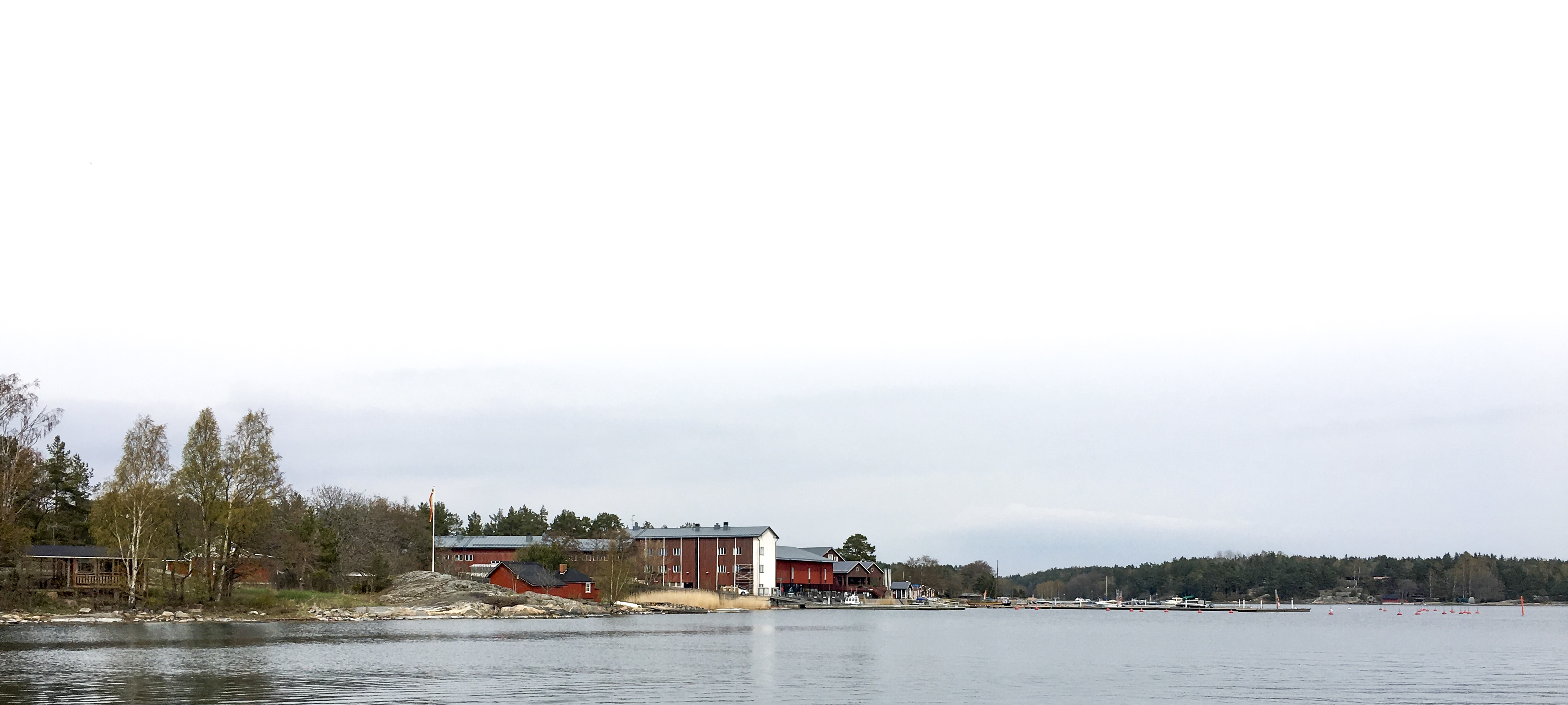 En vy fårn havet, ett stort rött hus på stranden.